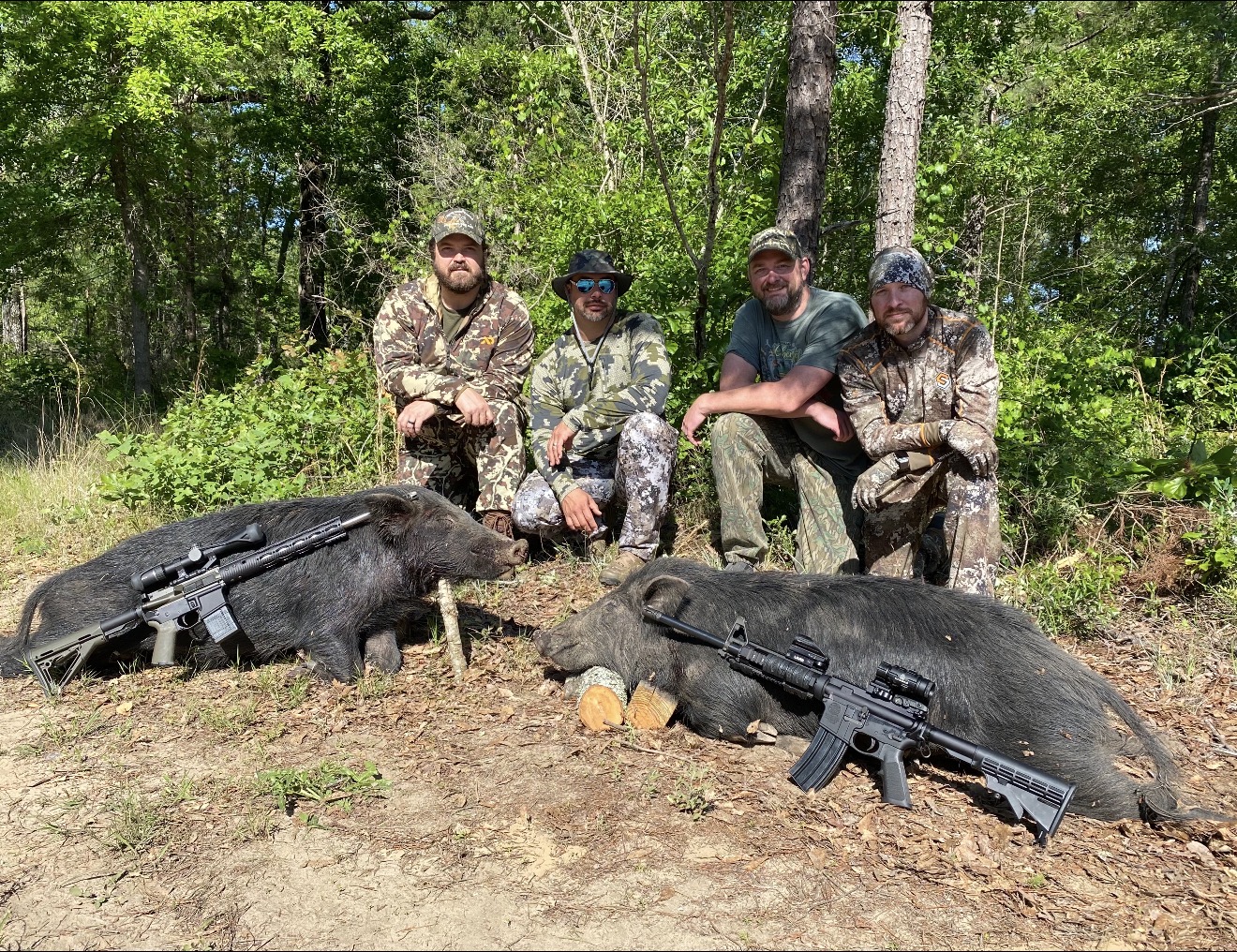 Crew with two black hogs and their rifles.